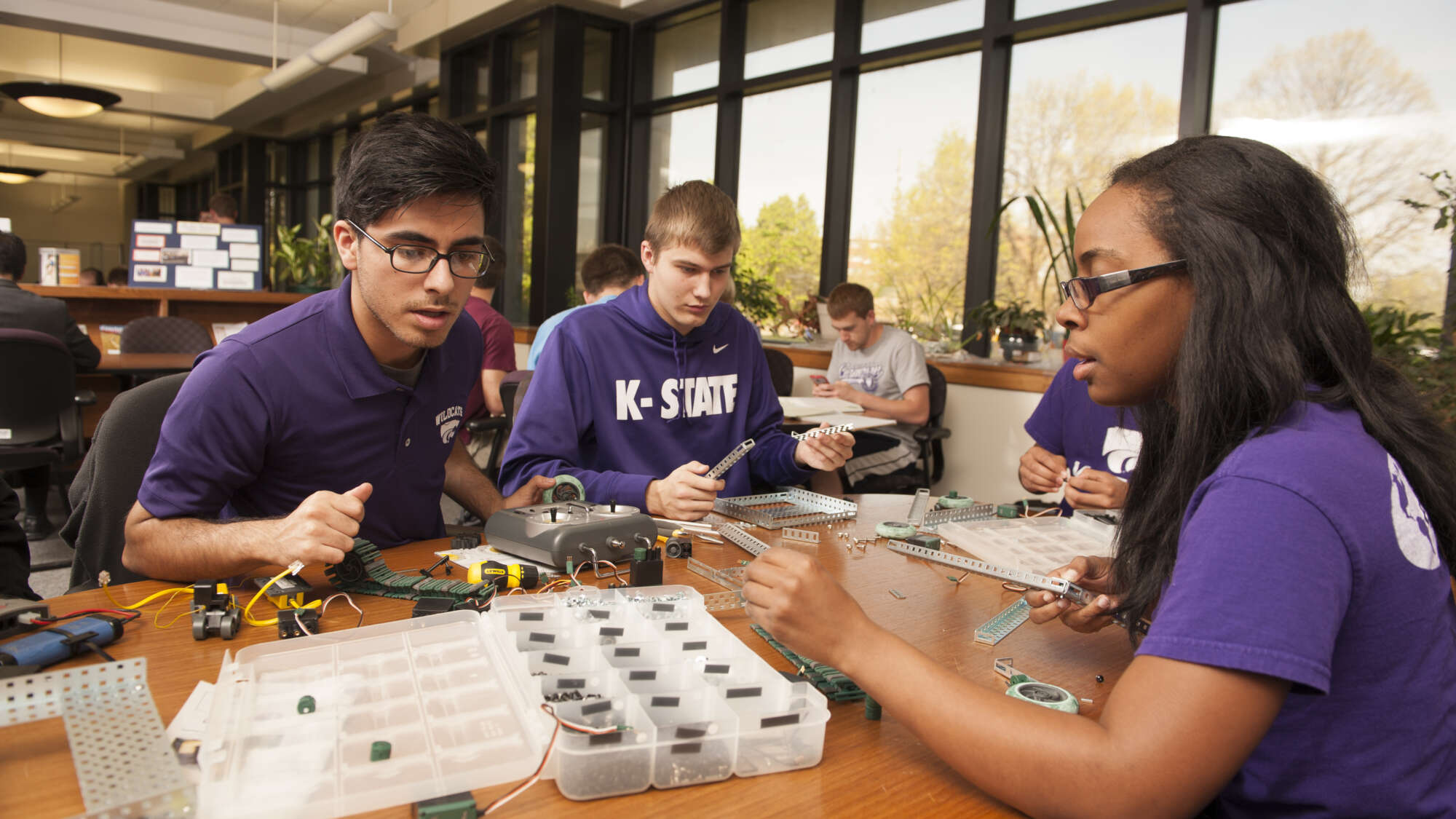 Three engineering students studying around a desk