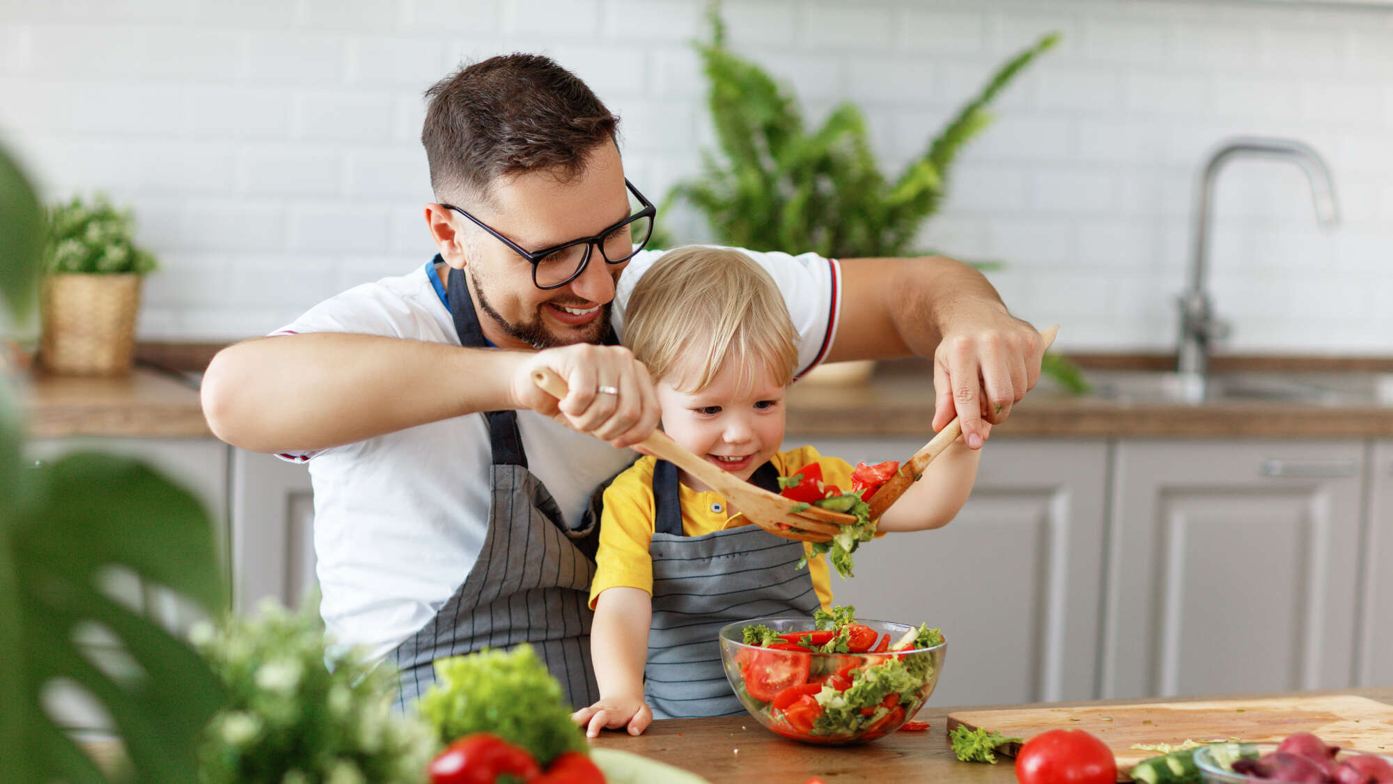 man and child preparing a salad to eat
