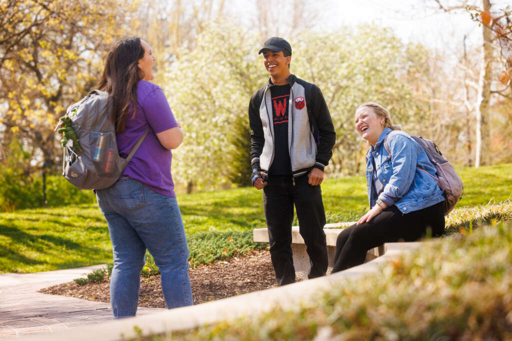 three students talk on campus