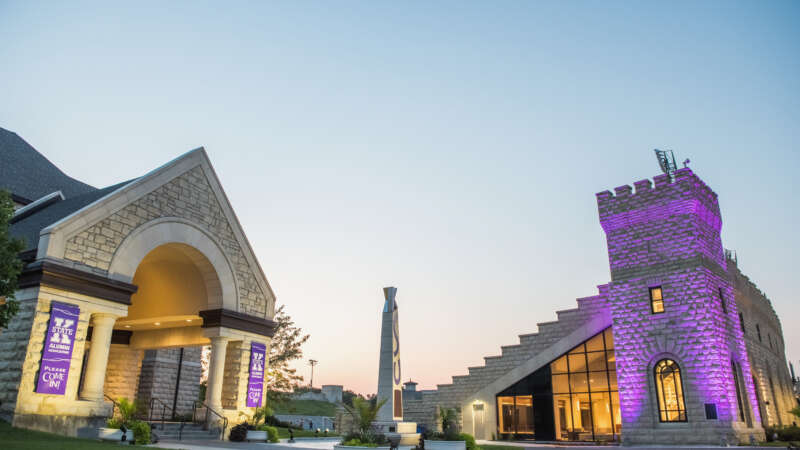 Alumni association building with memorial stadium in the background with purple lights