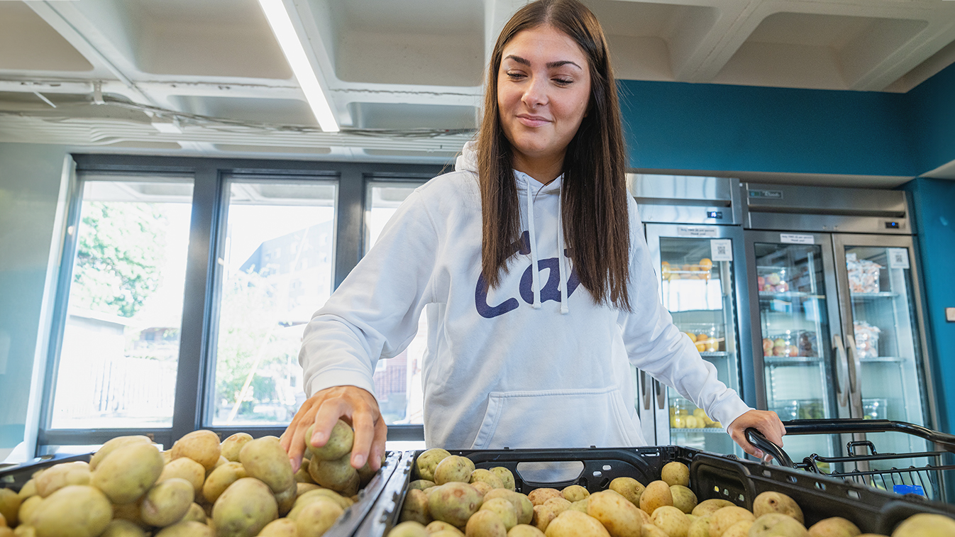 A student shops for fresh produce at Cats' Cupboard