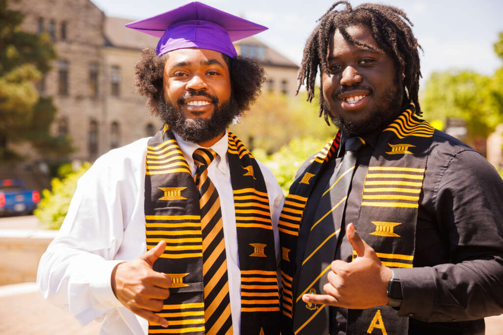 two men standing together outside of graduation 