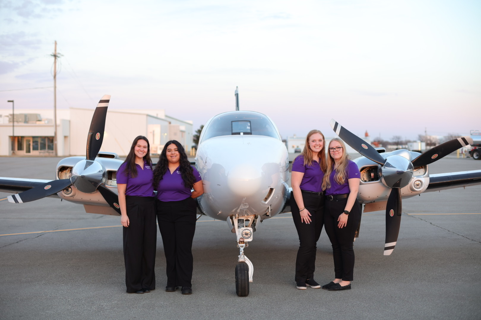 four salina women students standing next to plane