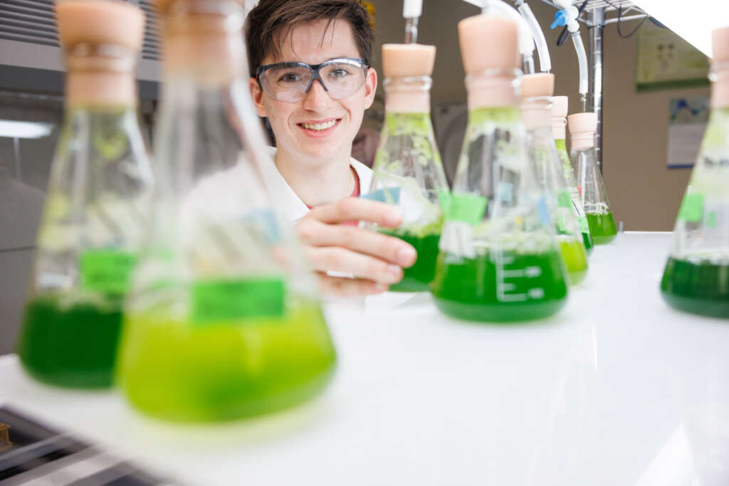 person standing behind science beakers 