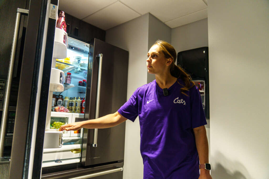student athlete opening refriderator stocked with food and drinks