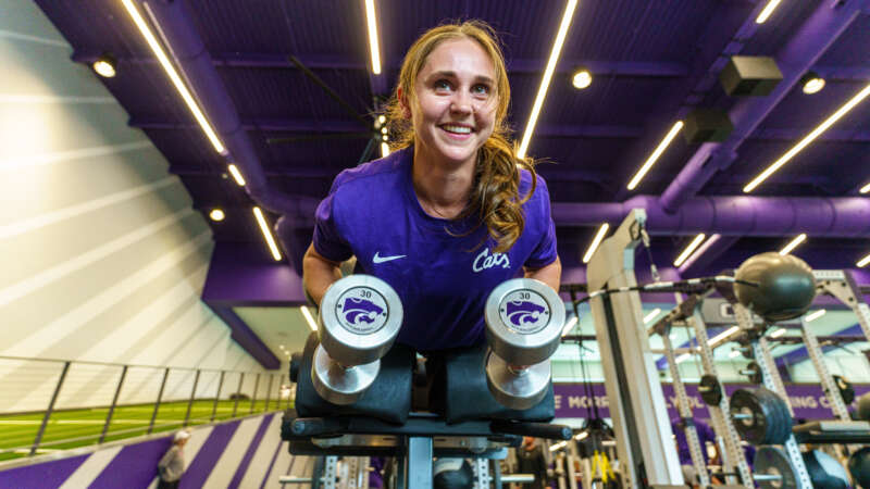 student lifting weights in a gym