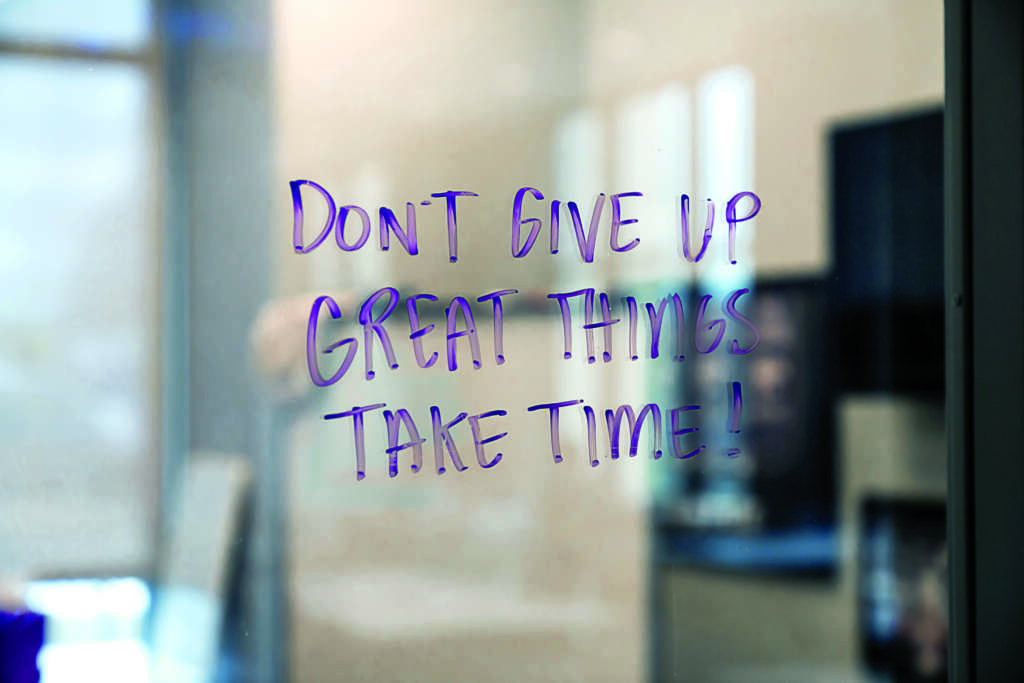 Purple dry erase marker text on clear glass reading "don't give up great things take time!"