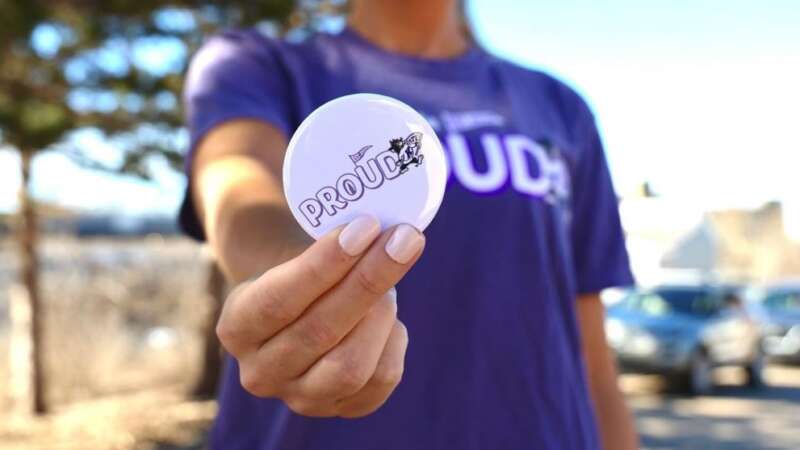 student holding a K-state proud button