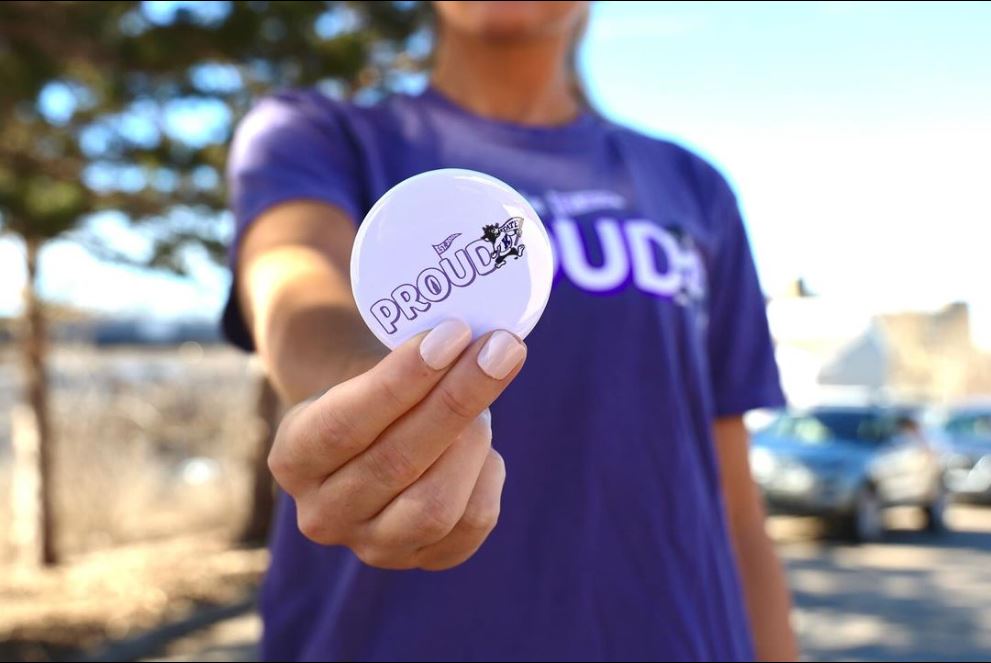 student holding a K-state proud button