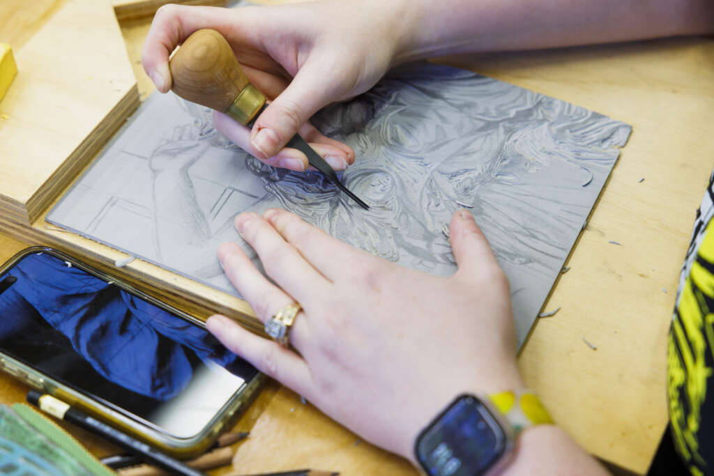 students hands carving a linoleum block print
