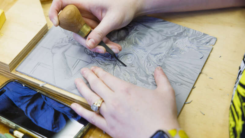 students hands carving a linoleum block print