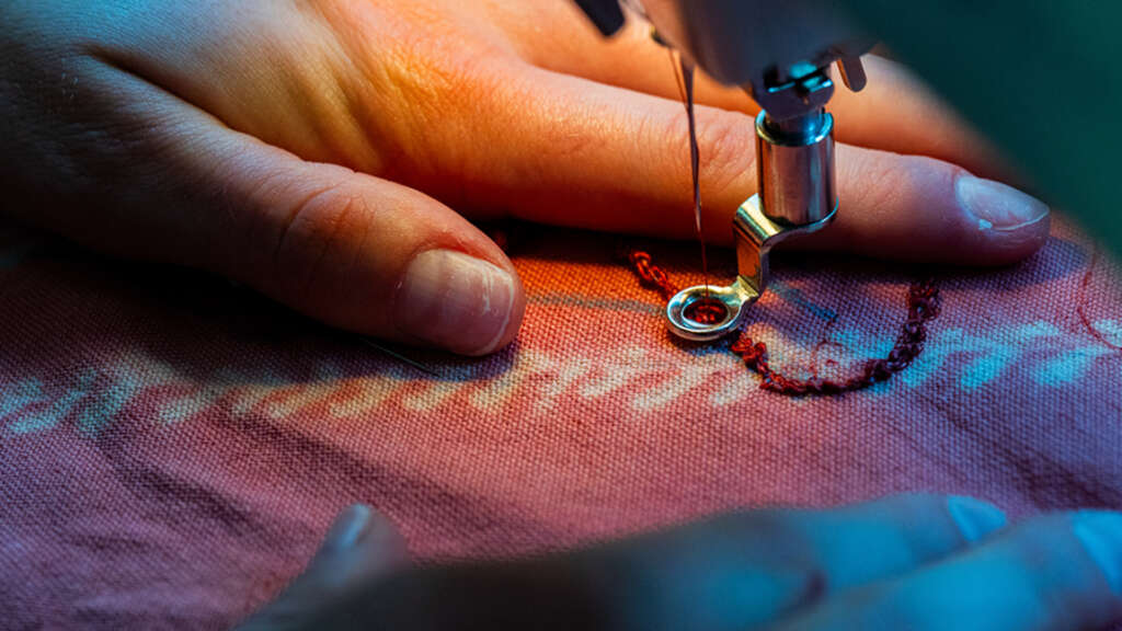 student sews a custom garment from sustainably dyed fabrics