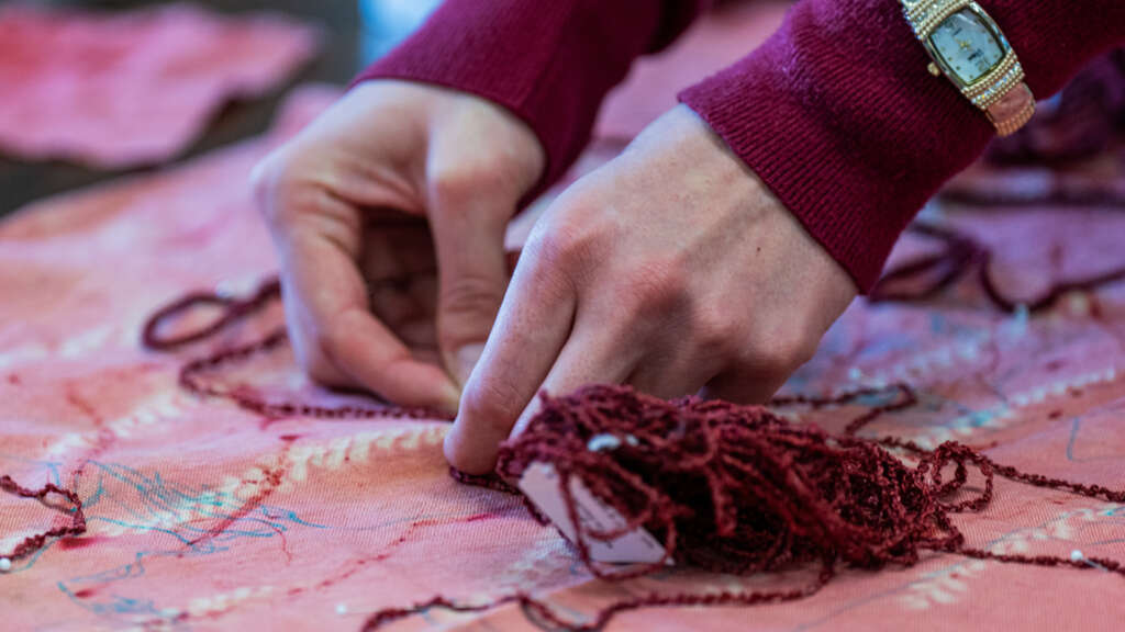 student hands working on a naturally dyed garment