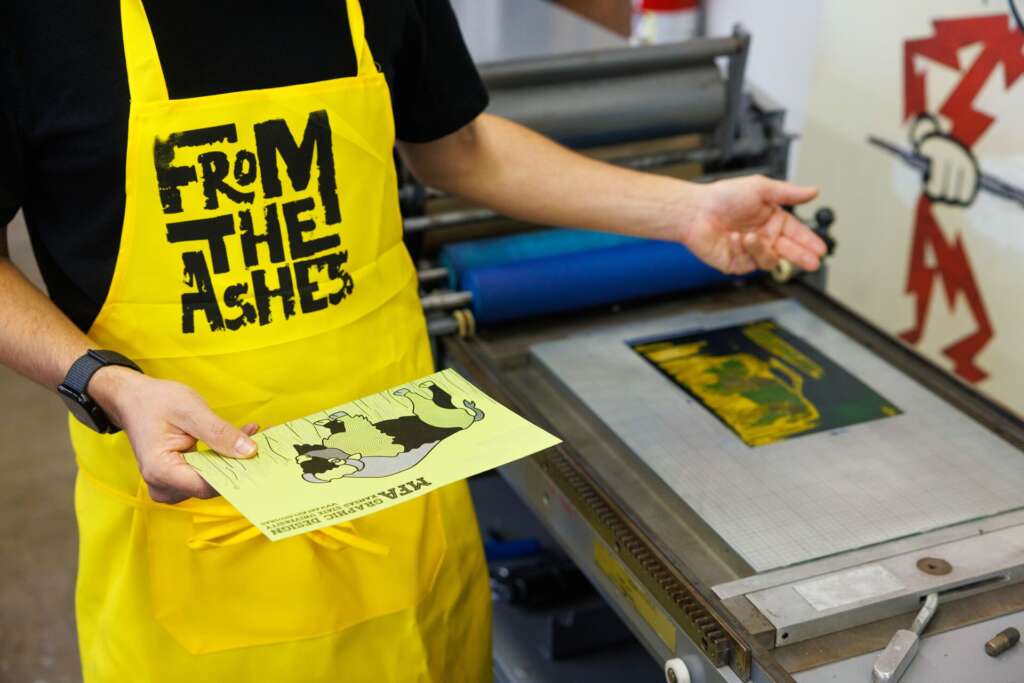 student holds a screen printed postcard