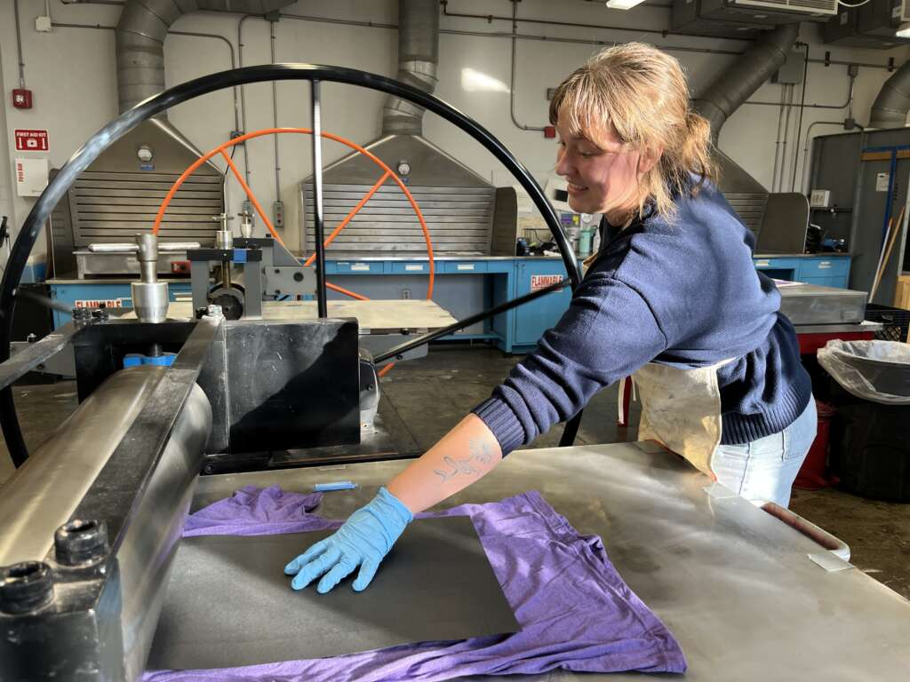 student printing a hand-carved design onto a purple t-shirt